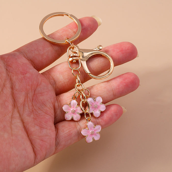 Wholesale Cherry blossom metal keychains available in various colors.
