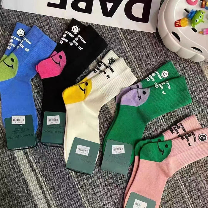 Wholesale Colorful socks with smiley face and letter print on the outside, with a pile of socks in the middle